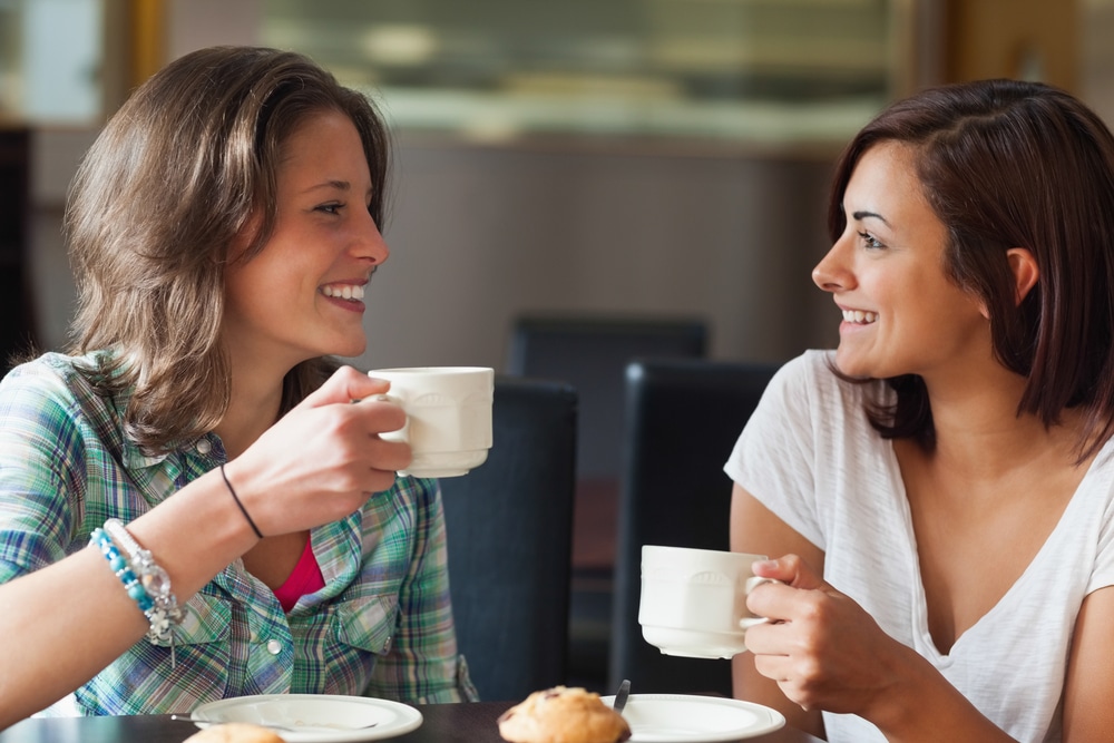 Two,Smiling,Students,Having,A,Cup,Of,Coffee,In,College